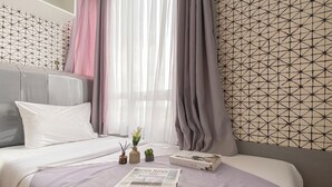 A neatly made bed with a white pillow, a small vase with flowers, and a book on the bed. - 2Br Near Mall At Cinere Bellevue Suites Apartment (Depok)