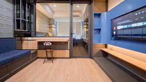 A modern kitchen with a wooden countertop, a chair, and a TV mounted on the wall displaying a streaming service interface. - 1Br Near Binus Alam Sutera At Collins Boulevard Apartement (Tangerang)
