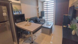 A modern kitchen with a dining area, a black sofa, and a coffee table. - 2Br Near Marvell City Mall At Linden Apartment (Surabaya)