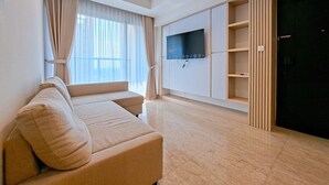 A modern living room with a beige sofa, a flat-screen TV mounted on the wall, and a sliding door closet. - Exclusive And Modern 2Br Apartment Branz Bsd City (Pagedangan)