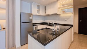 A modern kitchen with white cabinetry, a black countertop, and a built-in sink. - Exclusive And Modern 2Br Apartment Branz Bsd City (Pagedangan)