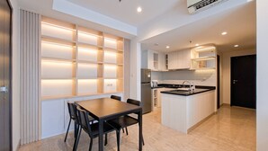 A modern kitchen with a central island, built-in cabinets, and a dining area with a table and chairs. - Exclusive And Modern 2Br Apartment Branz Bsd City (Pagedangan)