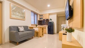 A compact living space with a sofa, a small kitchen area, and a flat-screen TV mounted on the wall. - Basic 2Br Apartment At Meikarta Near Dian Harapan School (Cikarang)