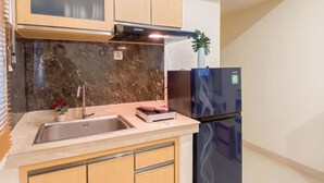 A kitchen with a sink, a microwave, a stove, and a refrigerator. - Basic 2Br Apartment At Meikarta Near Dian Harapan School (Cikarang)