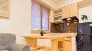 A compact kitchen with a wooden table, a built-in oven, and a refrigerator. - Basic 2Br Apartment At Meikarta Near Dian Harapan School (Cikarang)