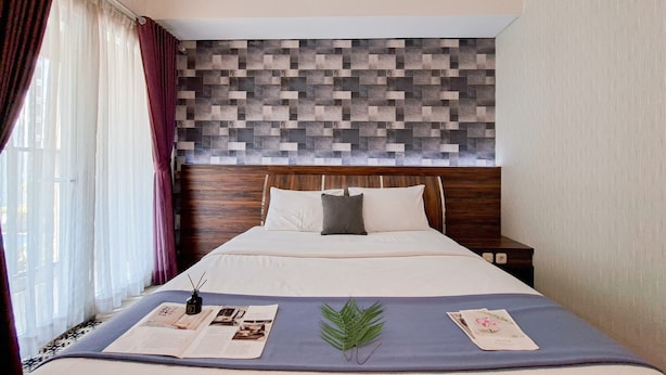 A neatly made bed with a blue bedspread, a wooden headboard, and a decorative wall panel.