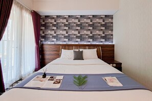 Ein ordentlich bezogenes Bett mit blauer Bettdecke, einem Holz-Kopfteil und einer dekorativen Wandverkleidung.