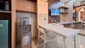 A modern kitchen with a stainless steel refrigerator, a water dispenser, and a flat-screen TV mounted on the wall.