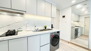 A modern kitchen with a built-in washing machine, a sink, and a compact countertop. - Modern Classic Touch 1Br Apartment At Tokyo Riverside Pik 2 (Teluknaga)