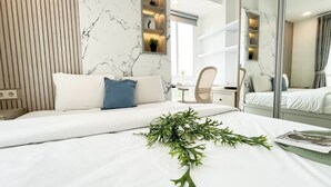 A modern hotel room with a bed, a bedside table, a mirror, and a window. - Modern Classic Touch 1Br Apartment At Tokyo Riverside Pik 2 (Teluknaga)