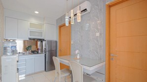 A modern kitchen with a marble backsplash, stainless steel appliances, and a glass dining table with chairs. - 2Br Apartment Connected To Mall At Cinere Bellevue Suites (Depok)