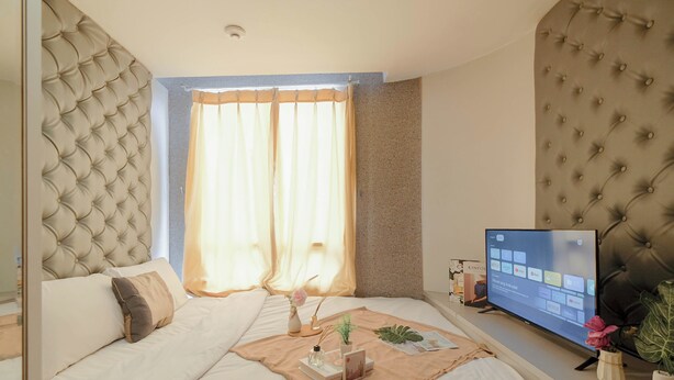 A bedroom with a large bed, a television on a stand, and a window with curtains. - 2Br Apartment Connected To Mall At Cinere Bellevue Suites (Depok)