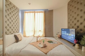Ein Schlafzimmer mit einem großen Bett, einem Fernseher auf einem Schrank und einem Fenster mit Vorhängen.