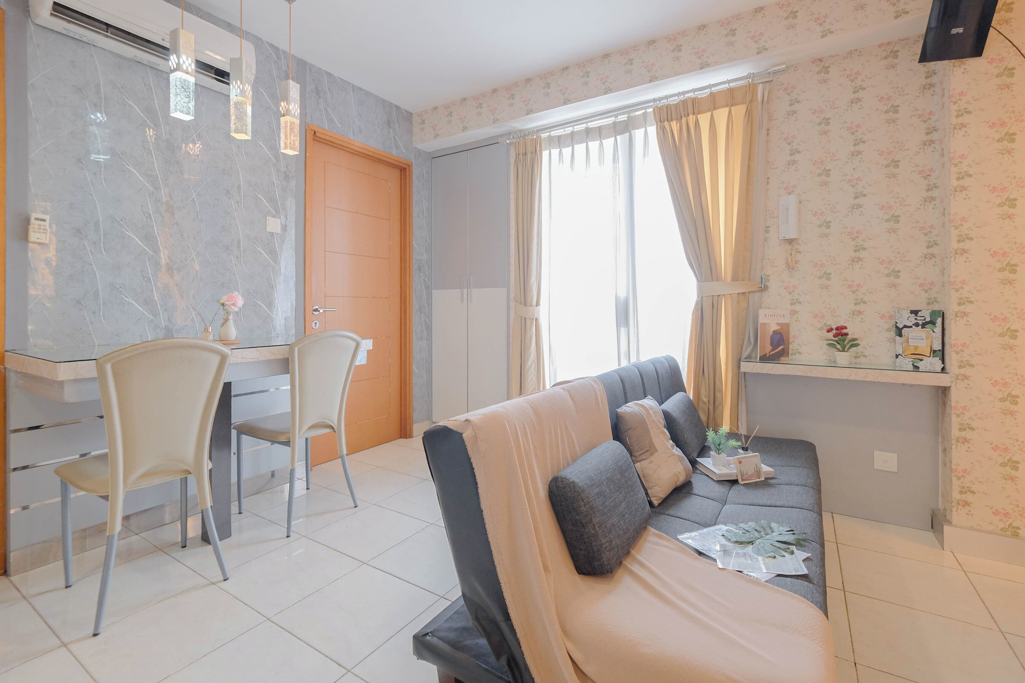 A modern living room with a sofa, a dining area with chairs, a TV mounted on the wall, and a window with curtains.