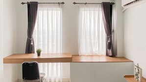A room with a wooden desk, a chair, and two windows with sheer curtains. - Studio Near Bekasi Station At Patraland Urbano Apartment (Bekasi)