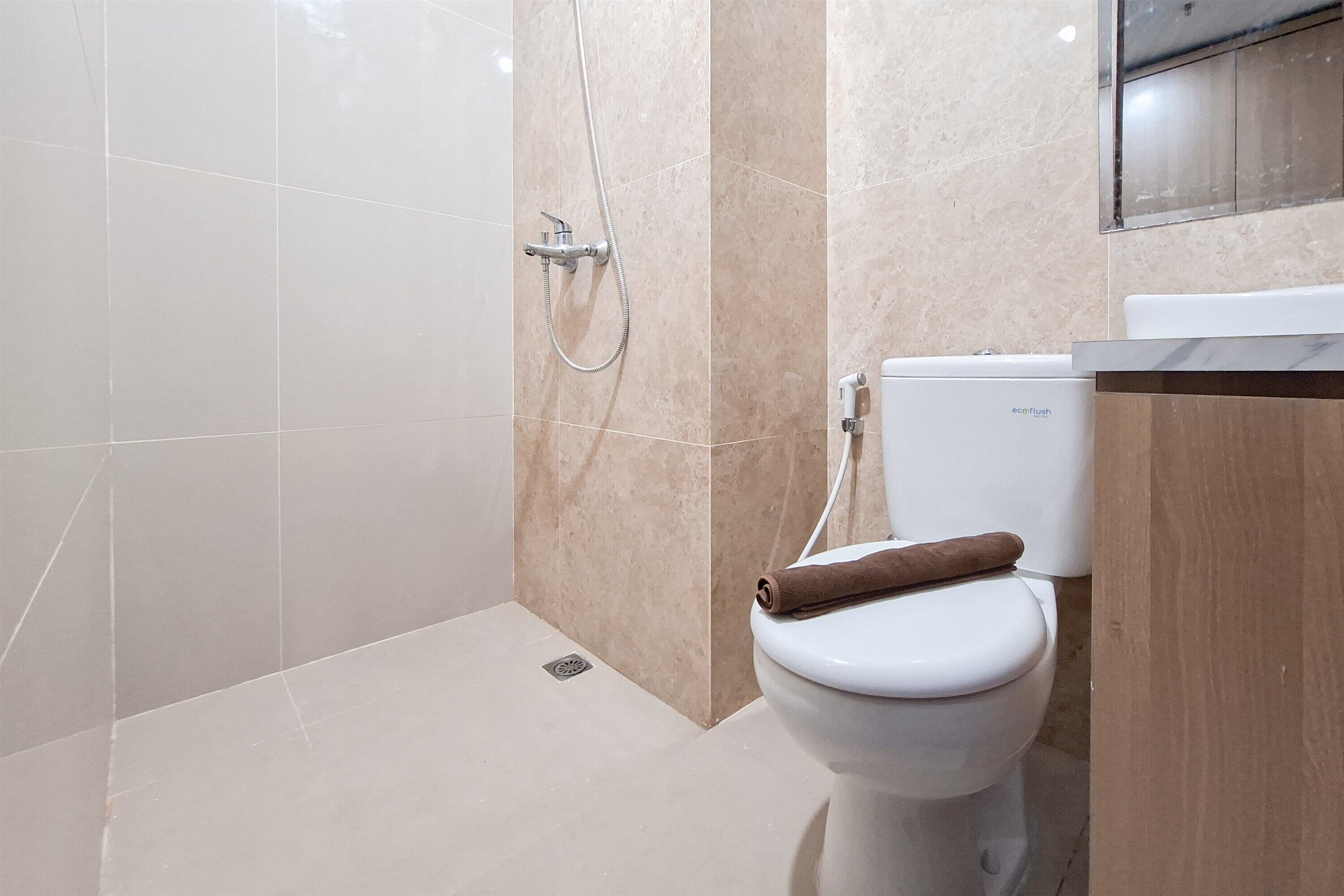 A modern bathroom with a toilet, shower, and a marble-tiled wall.