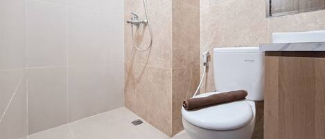 A modern bathroom with a toilet, shower, and a marble-tiled wall.