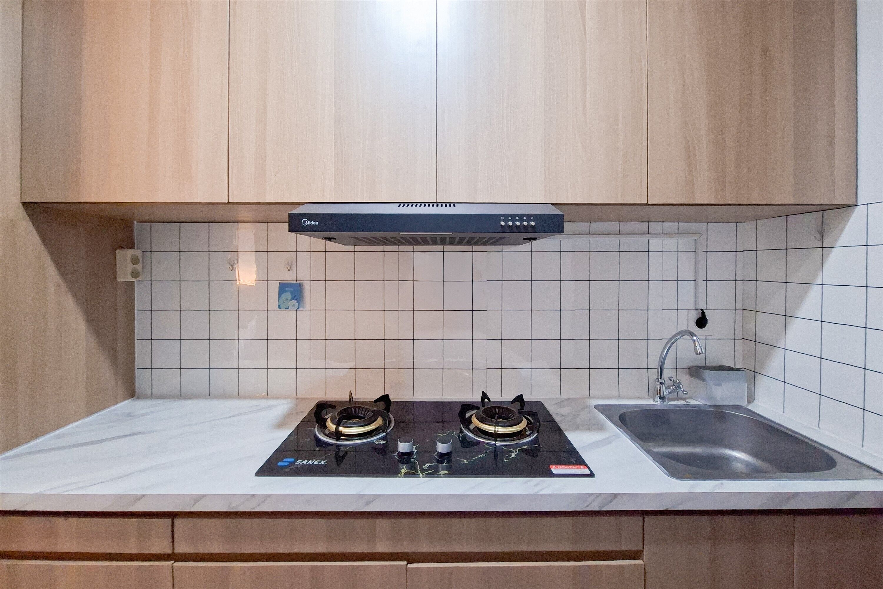 A kitchen with two gas stoves, a stainless steel sink, and wooden cabinets.