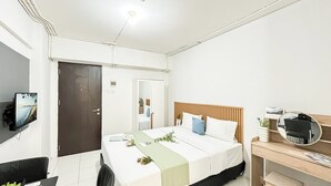 Une chambre d’hôtel équipée d’un lit, d’une table de chevet, d’un miroir et d’un téléviseur fixé au mur.