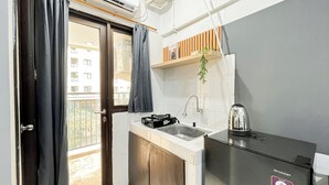 Une cuisine compacte équipée d’un évier, d’une bouilloire et d’un réfrigérateur de la marque Sharp.