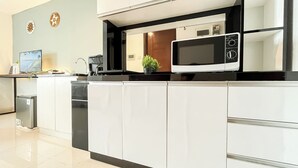 A modern kitchen with white cabinets, a built-in microwave, and a small sink. - Modern And Tidy Studio Room At West Vista Apartment (Jakarta)
