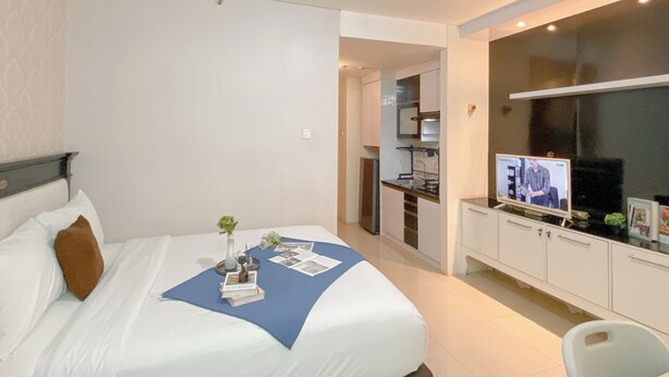 Ein Hotelzimmer mit Bett, Schreibtisch und Fernseher.
