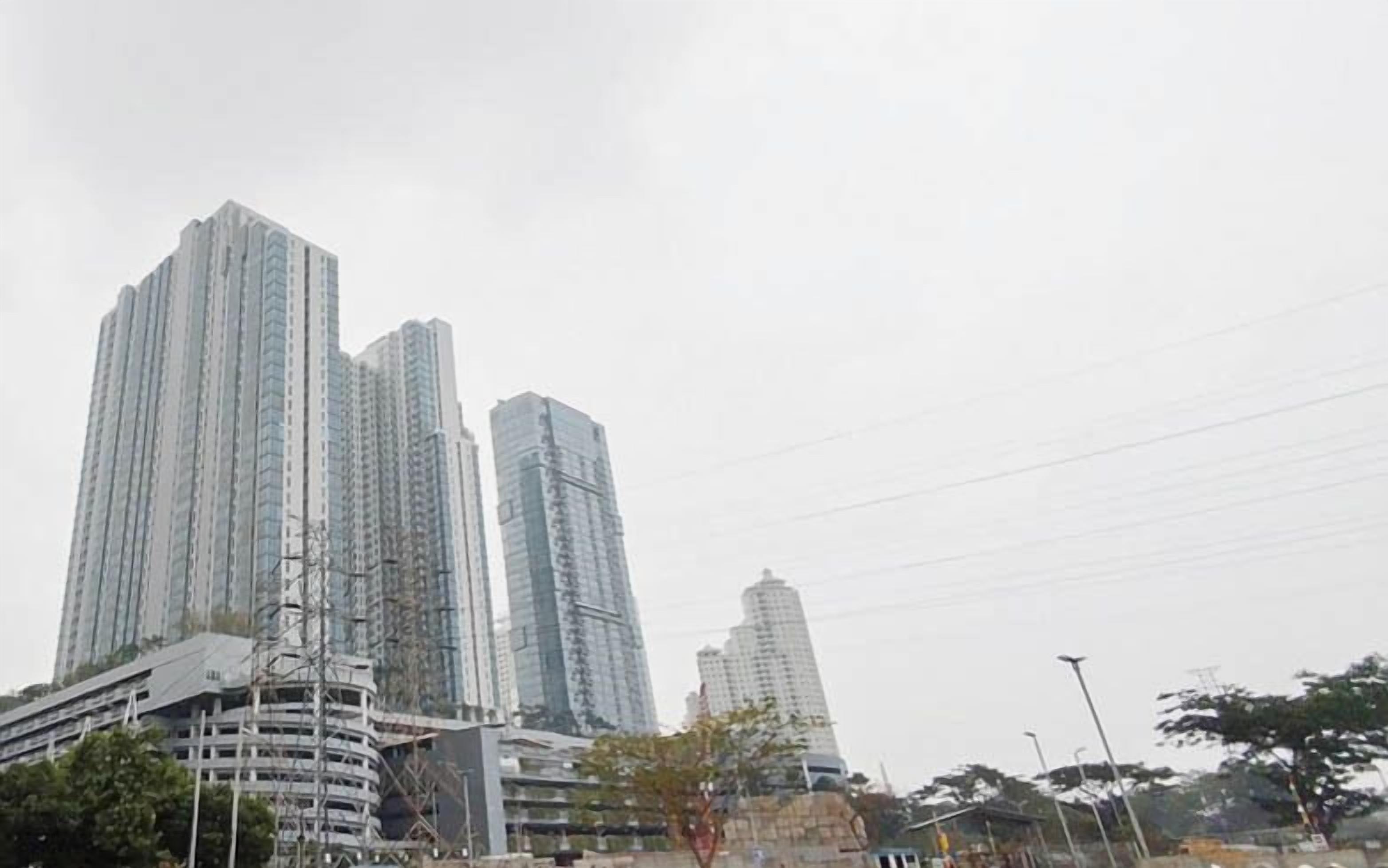 Un paysage urbain avec de nombreux immeubles de grande hauteur, dont une structure incurvée remarquable et plusieurs gratte-ciel aux lignes droites.