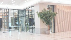 A spacious lobby with a large glass partition, a potted plant, and a modern design. - Studio Near Mall (No Kitchen) At Benson Supermall Mansion Apartment (Surabaya)