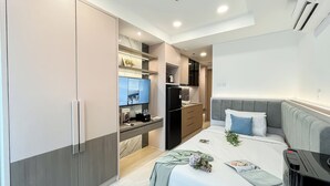 A compact bedroom with a bed, bedside table, and a small kitchenette. - Strategic Studio At Antasari Place Apartment (Jakarta)