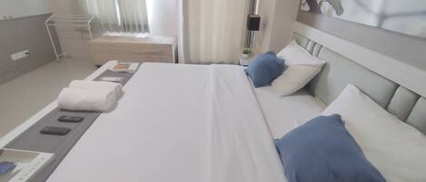 A hotel room with a neatly made bed, a bedside table with a lamp, and a window with curtains.