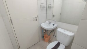 A bathroom with a toilet, sink, and mirror. - Spacious And Modern Studio At Tanglin Supermall Mansion Apartment (Surabaya)