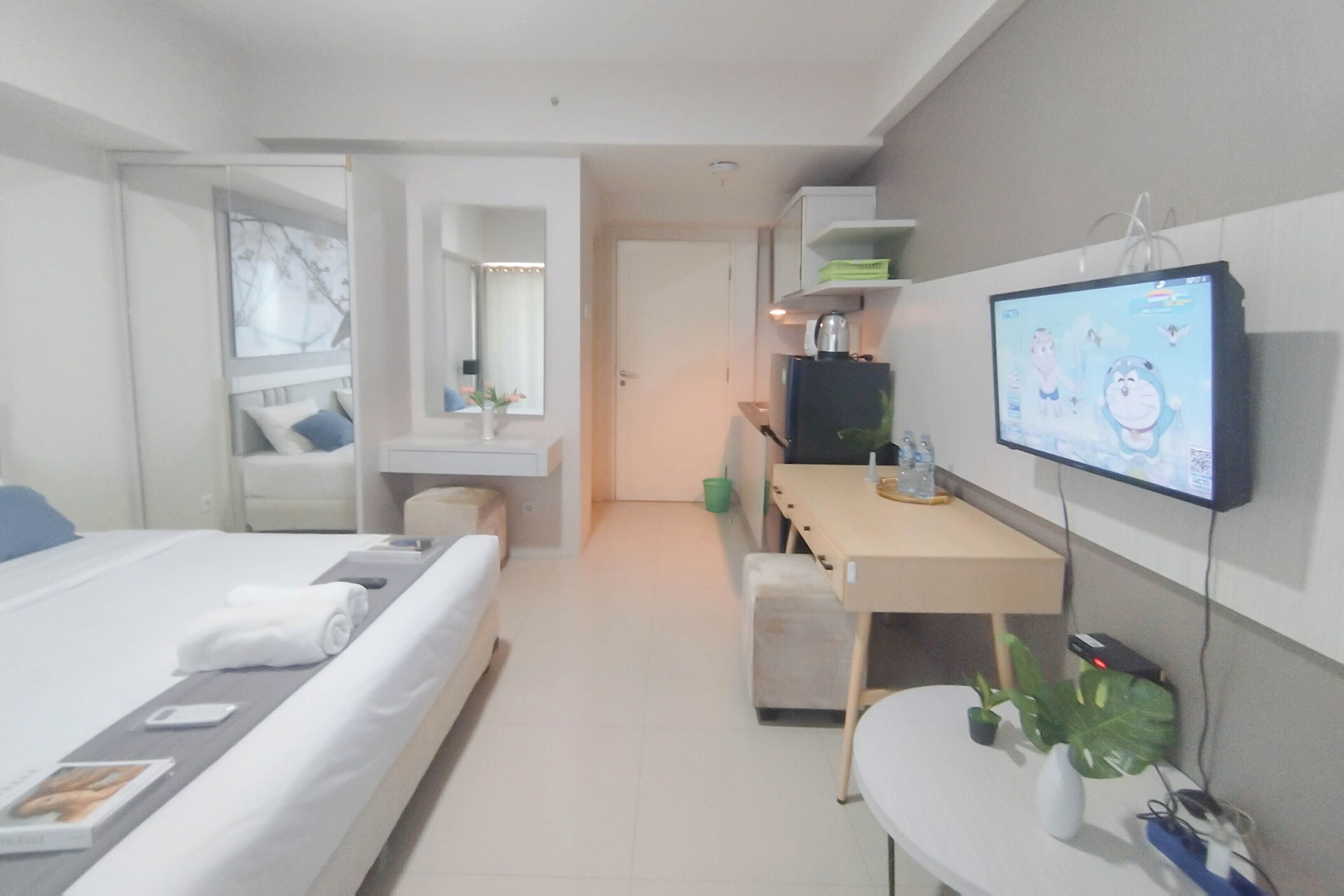Une chambre d’hôtel moderne équipée d’un lit, d’un bureau, d’une télévision et d’une petite plante.