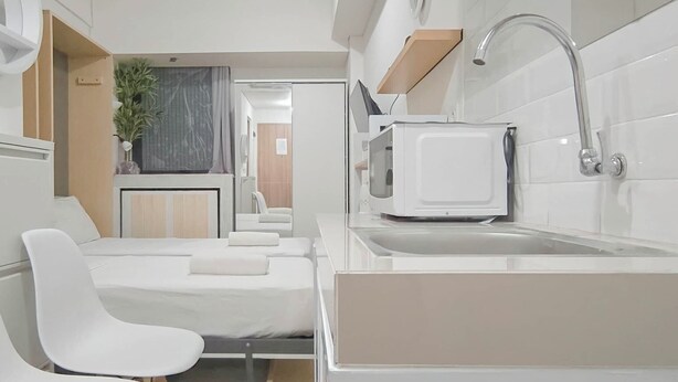 A compact, modern kitchenette with a microwave, sink, and a small dining area with a chair. - Small Studio (No Kitchen) Apartment At Bandaraya - Tallasa City Makassar (Makassar)