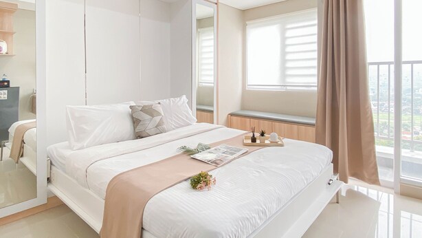 Um quarto moderno com uma cama grande, um guarda-roupa, uma mesa de cabeceira com uma planta e uma janela com cortinas.