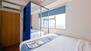 Ein Hotelzimmer mit Bett, Fenster mit Blick, Spiegel und Klimaanlage.