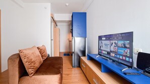 Ein modernes Wohnzimmer mit einer Couch, einem Flachbildfernseher, einem Kühlschrank und Holzschränken.