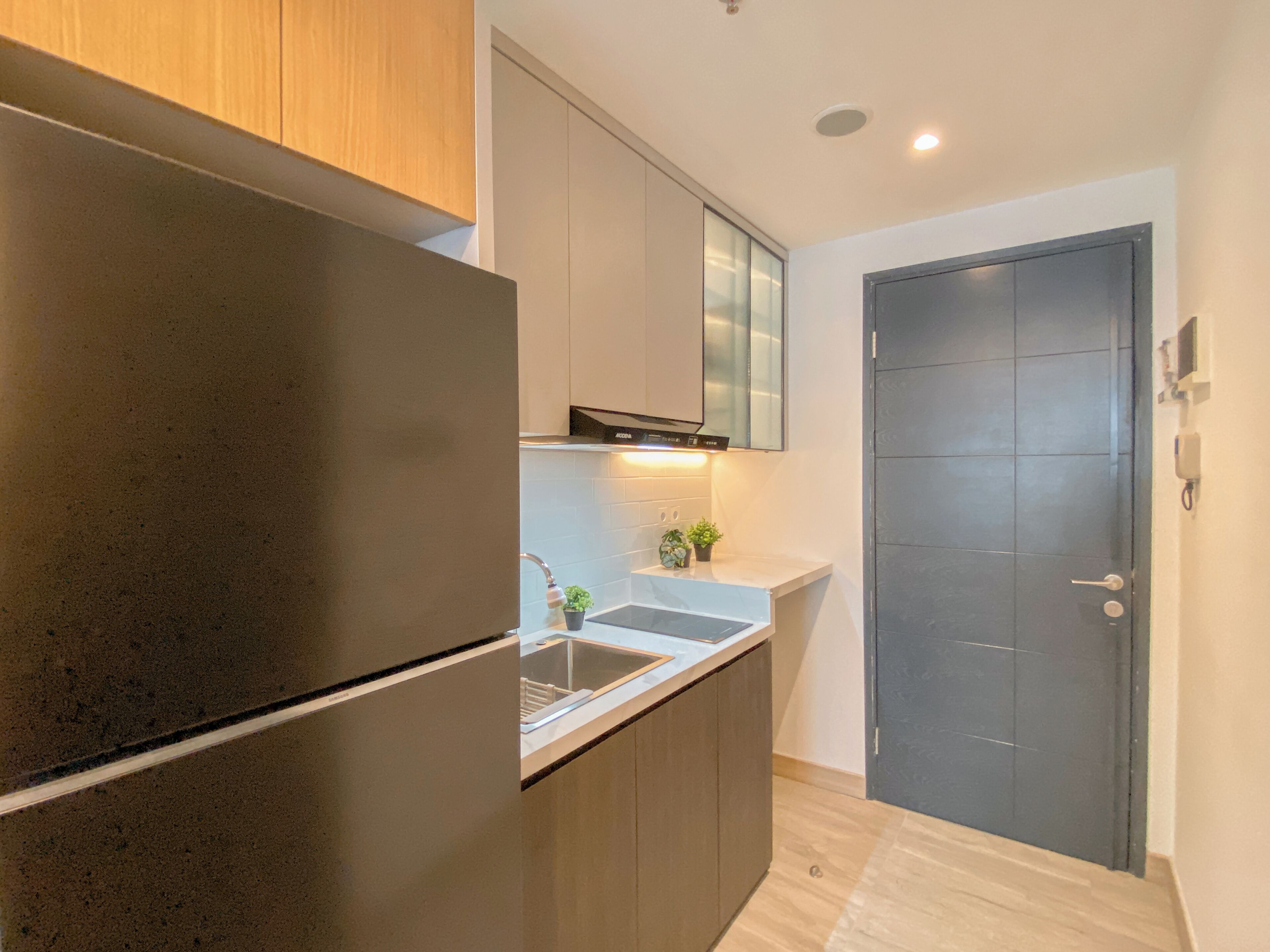 A modern kitchen with a built-in refrigerator, stainless steel sink, and a dark wooden cabinet.