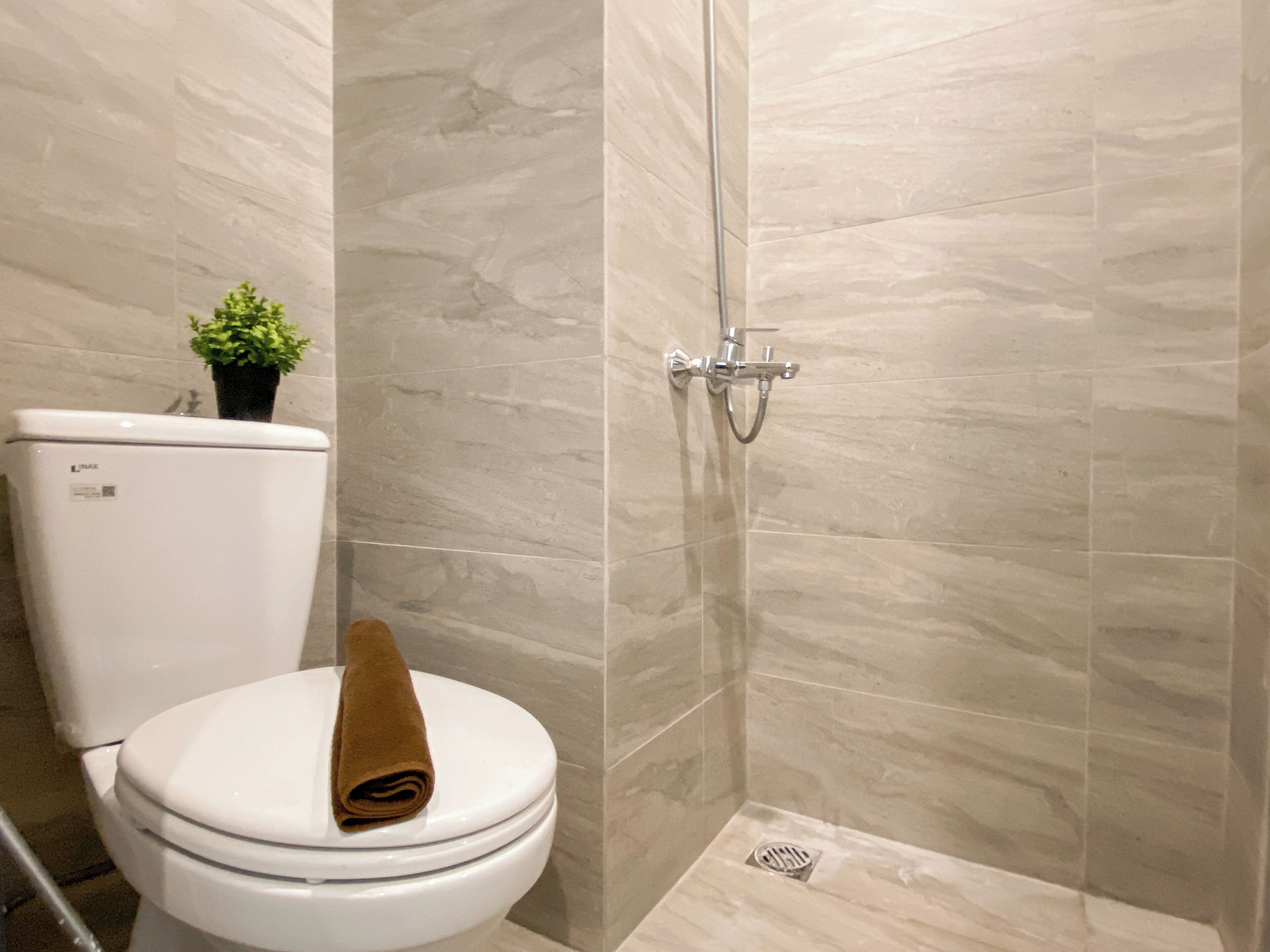 Une salle de bain avec des toilettes, une douche et une plante en pot.