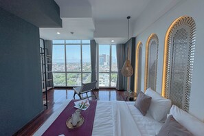 A modern hotel room with a large window, a bed, a chair, and a small table. - 1Br Near Uinsa At Tamansari Papilio Apartment (Surabaya)