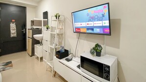 A modern living room with a flat-screen TV mounted on the wall, a white cabinet below it, and a black-framed clock above.