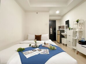 Een hotelkamer met een bed, een klein bureau, een witte inbouwkast, een badkamer en een deur.