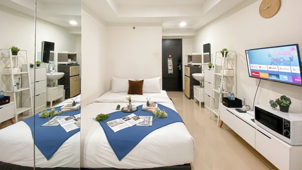 A modern hotel room with a large bed, a TV, a desk, and a bathroom.