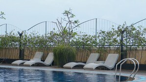A pool area with lounge chairs and a metal ladder.