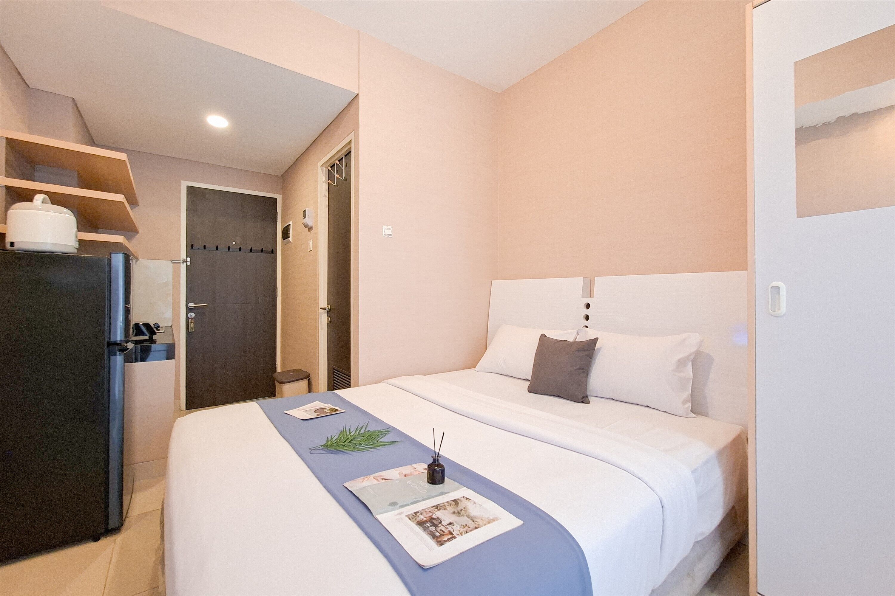 Une chambre d’hôtel comprenant un lit, un bureau avec un réfrigérateur et une porte donnant accès à une salle de bain.