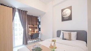 Habitación de hotel con cama, escritorio y ventana con cortinas.