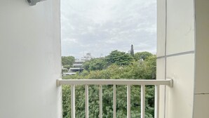 A balcony with a white railing, overlooking a cityscape with buildings and trees. - Pure Nest Studio At Candiland Apartment (Semarang)