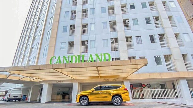 A hotel entrance with a yellow SUV parked in front, a covered lobby area, and a multi-story building with balconies. - Pure Nest Studio At Candiland Apartment (Semarang)