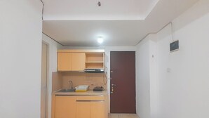 A compact kitchen with wooden cabinets, a sink, and a countertop. - 1Br Near Gedebage Station At Tamansari Panoramic Apartment (Bandung)