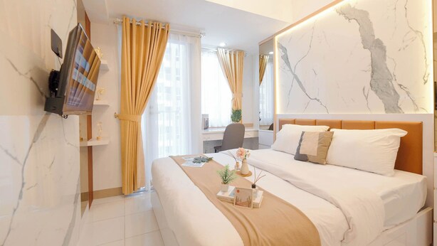 A modern hotel room with a large bed, a desk, a TV, and a marble wall. - Marble Haven Studio At Tokyo Riverside Pik 2 Apartment (Teluknaga)