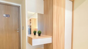 A modern bathroom with a wooden vanity, a mirror, and a small stool. - Warm Minimalist Studio Apartment Near Paramadina University At Meikarta (Cikarang)